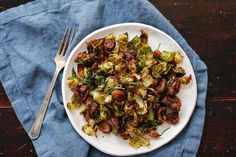 a white plate topped with brussel sprouts next to a fork