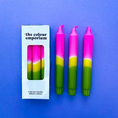 three pink, green and yellow pens sitting next to each other on a blue surface