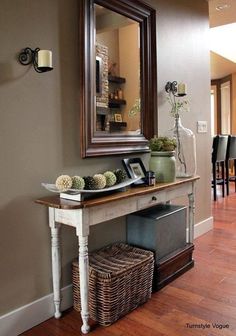 a hallway with a mirror, vases and other items on the table in front of it