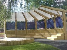 a wooden gazebo sitting on top of a lush green field next to a park