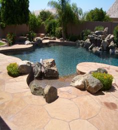 a pool with rocks and water features a fountain