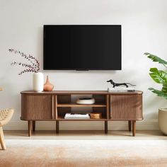 a flat screen tv mounted on the wall above a wooden entertainment center in a living room