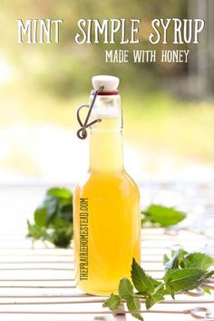 a bottle filled with lemonade sitting on top of a table next to mint leaves