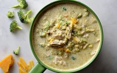 broccoli and cheese soup in a green bowl with some crackers on the side