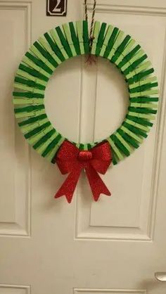 a green and red christmas wreath hanging on a door