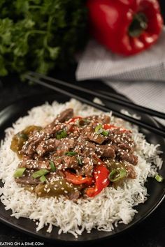 a black plate topped with rice and meat