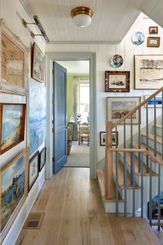 a hallway with wooden floors and pictures on the wall next to the stair railings