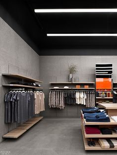 the inside of a clothing store with clothes on shelves