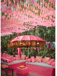 pink and gold wedding decor with an umbrella in the middle, flowers hanging from the ceiling