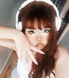 a woman with red hair wearing headphones and holding her hand up to her face