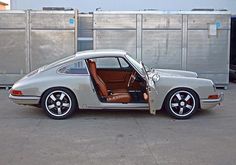 an old car with its door open sitting in a parking lot