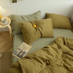 a bed with green sheets and pillows on top of it next to a night stand