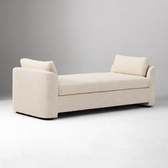 a white couch sitting on top of a white floor next to a gray wall in an empty room