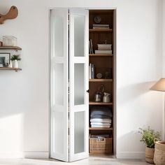 a tall white cabinet sitting in the corner of a living room next to a lamp