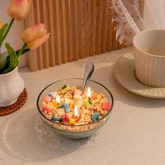 a bowl filled with cereal and marshmallows on top of a table next to a cup