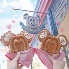 two people holding up mickey mouse pretzels