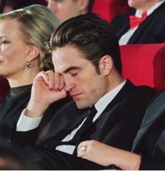 two people sitting next to each other in front of a crowd at a movie theater