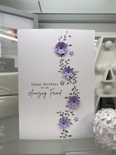 a white card with purple flowers and the words happy birthday to an amazing friend on it