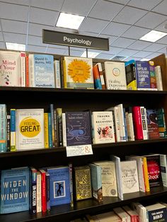 many books are stacked on the shelves in a book store with a sign above them