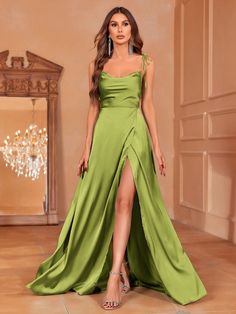 a woman in a green dress posing for the camera with her legs slited up