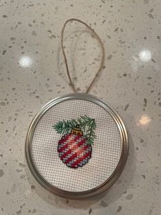 a cross stitch ornament hanging from a string on top of a white counter