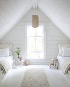 a bedroom with two beds and a rug on the floor in front of a window