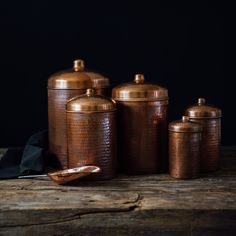 copper canisters are sitting on a wooden table