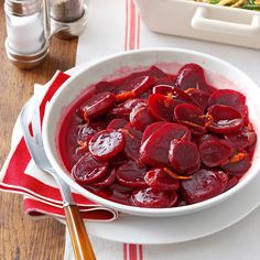 a white bowl filled with sliced beets on top of a table next to other dishes