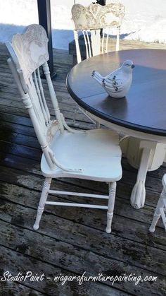 two white chairs sitting on top of a wooden table