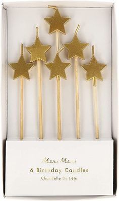 six gold star candles in a white box