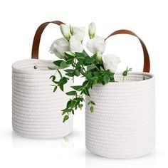 two white baskets with flowers in them sitting next to each other on a white surface