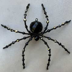 a black beaded spider sitting on top of a white surface