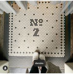 a person standing in front of a wall with hexagonal tiles on it and the words danko above them