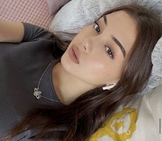 a young woman laying on top of a bed next to a pillow and blanket covered wall