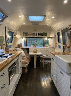 the interior of an rv with wood flooring and white cabinets, including a kitchen