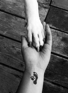 a person holding the hand of a dog with a foot print on it's wrist