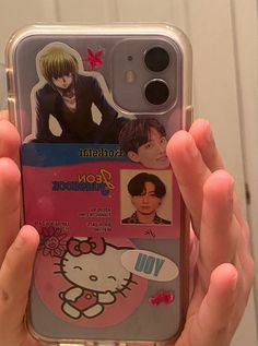 someone holding up their cell phone case with some pictures on it and hello kitty stickers