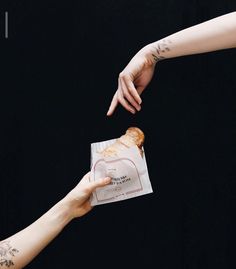 two people reaching out towards each other to grab something from a bag that is wrapped in paper