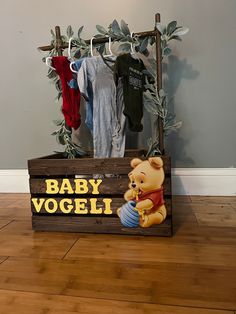 a wooden box with winnie the pooh baby vogeli on it and clothes hanging up