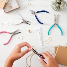 a person cutting paper with scissors and other crafting supplies on a white counter top