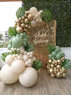 balloons and greenery are on display in front of a gold - colored birthday sign