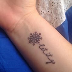 a snowflake tattoo on the wrist that says, let it snow and is written in cursive font