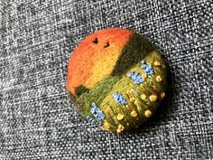 a button with flowers on it sitting on top of a gray fabric surface, next to a black and white cloth background