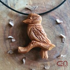 a wooden carved bird sitting on top of a necklace