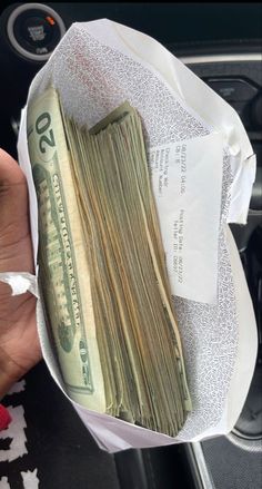 a bunch of money sitting in a bag on top of a car dash board,