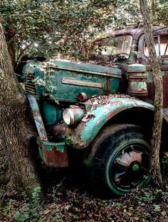 an old truck is parked in the woods