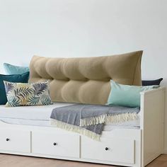 a day bed with drawers underneath it and pillows on the bottom shelf, in front of a white wall