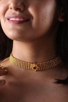 a close up of a woman wearing a gold choker and necklace with beads on it