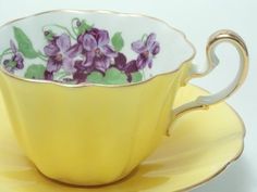 a yellow tea cup with purple flowers on it