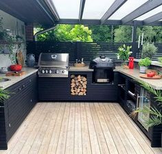 an outdoor kitchen with wood flooring and black cabinets